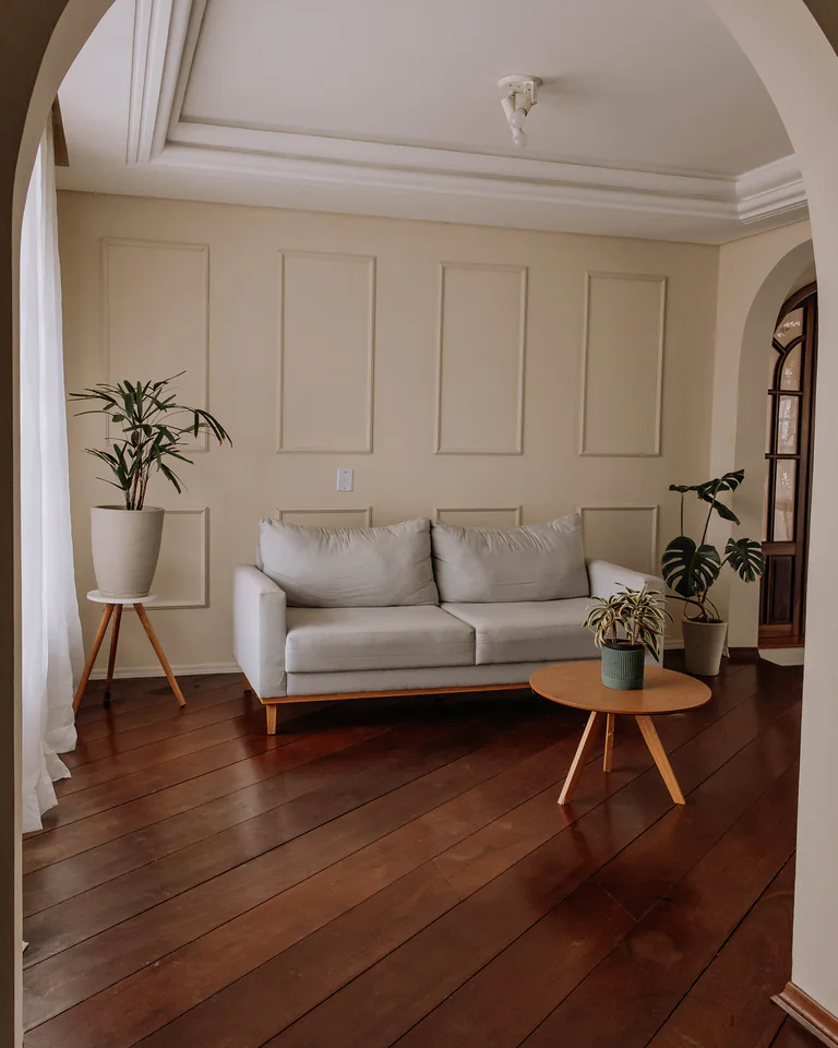 Sala vista através de um arco, com sofá, mesa de centro e plantas no Studio Keeper